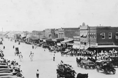 Black and white picture of Historic Downtown Bryan with horse-drawn carts and early automobiles.