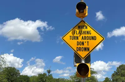 flashing roadway sign with text that says "When Flashing, Turn Around, Don't Drown"