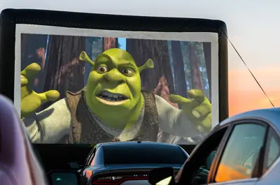 outdoor drive-up theater screen with Shrek projection