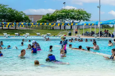 many families enjoying swimming in Bryan Aquatic Center's pool on a bright summer day