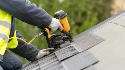 Roofer using a nail gun to nail down shingles.