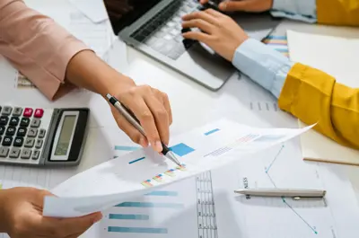 hands holding and documenting financial paperwork using a calculator.