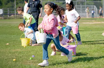 children running in a field to collect colorful eggs hidden in the grass