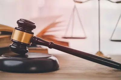 gavel laying next to a golden scale and law books