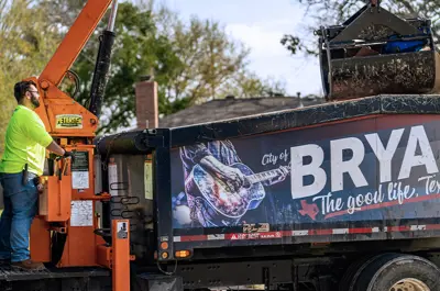 City of Bryan Solid Waste employee operating a truck crane arm.