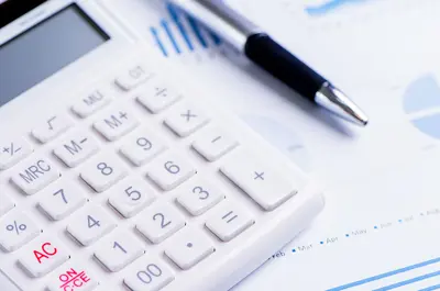 calculator and pen resting on top of financial paperwork